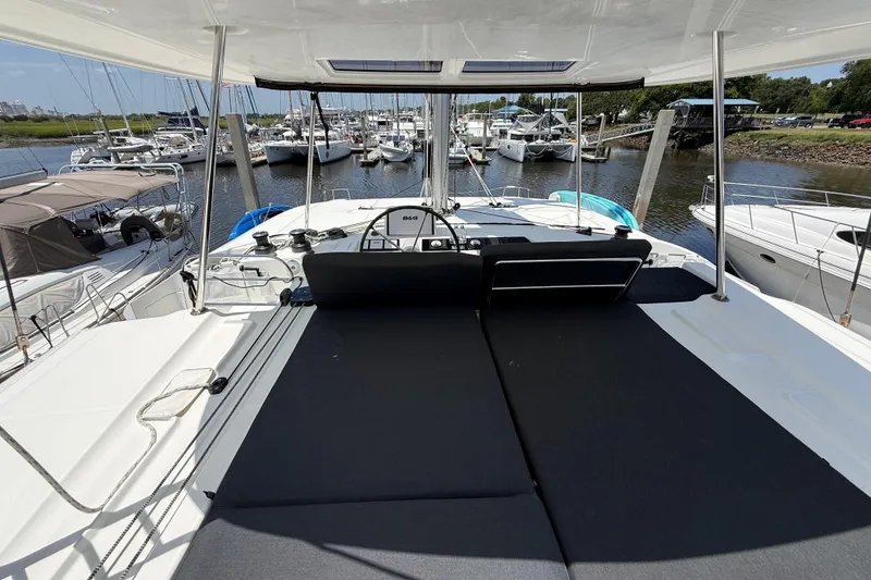 Slide: The Image of Luxurious 2021 Lagoon 46 catamaran docked at marina, showcasing spacious deck and helm. - 19