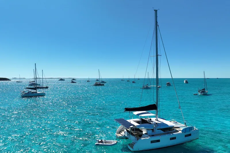 Slide: The Image of Sailboats on turquoise sea, featuring a 2021 Lagoon 46 catamaran under clear blue skies. - 5
