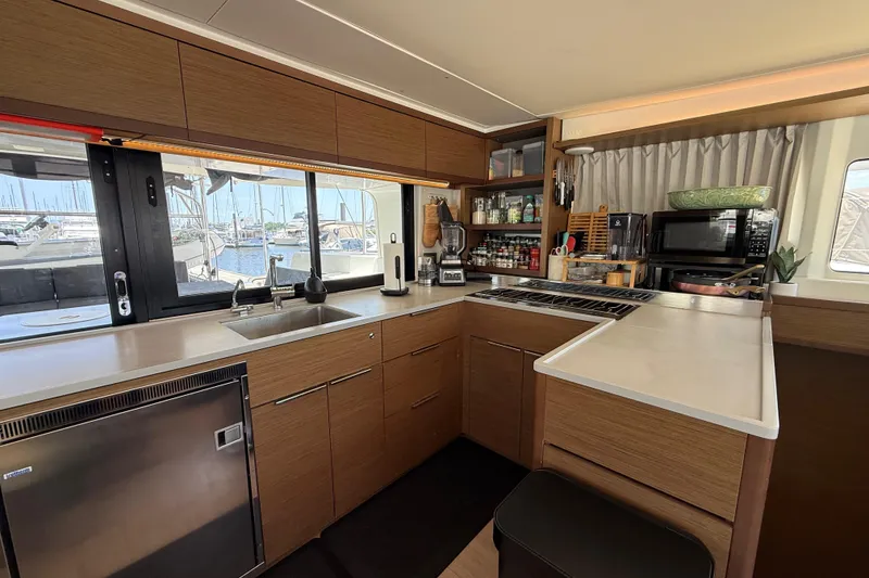 Slide: The Image of Modern kitchen interior on a 2021 Lagoon 46 catamaran, featuring sleek wood cabinetry and appliances. - 43