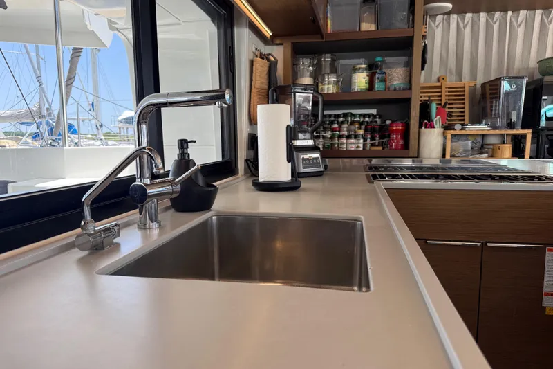 Slide: The Image of Modern kitchen interior on a 2021 Lagoon 46 yacht, featuring a sleek sink and organized shelves. - 41