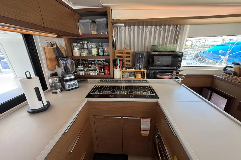 Slide: The Image of Modern kitchen interior on a 2021 Lagoon 46 catamaran, featuring appliances and organized shelves. - 40