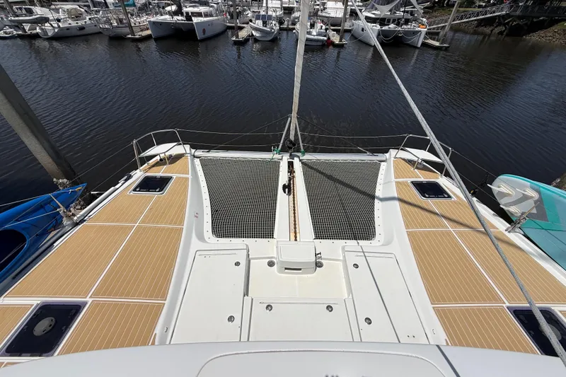 Slide: The Image of 2021 Lagoon 46 catamaran deck view at marina, showcasing spacious layout and netting. - 23