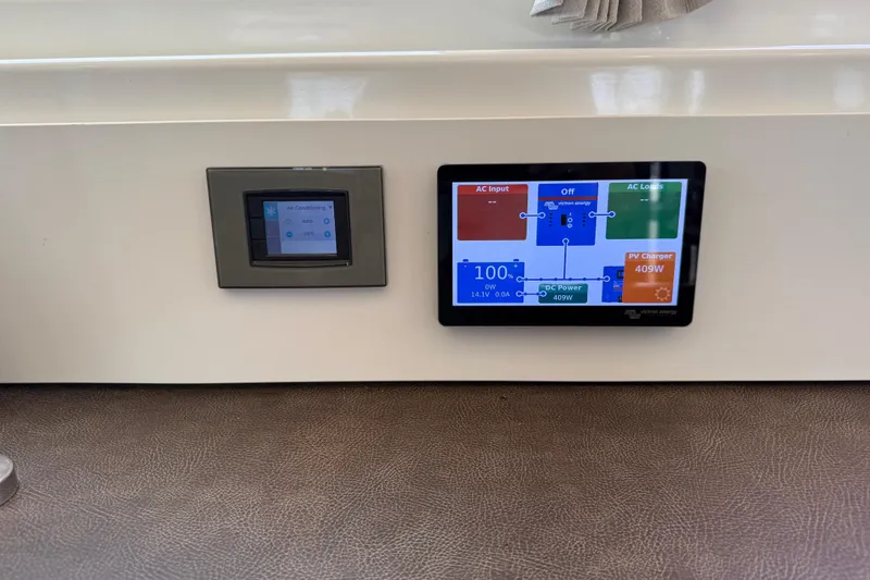 Slide: The Image of Control panels on a 2021 Lagoon 46 yacht, displaying air conditioning and power management systems. - 54