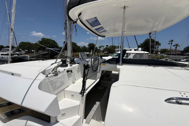 Slide: The Image of 2021 Lagoon 46 catamaran deck with helm station, docked under clear blue sky. - 13
