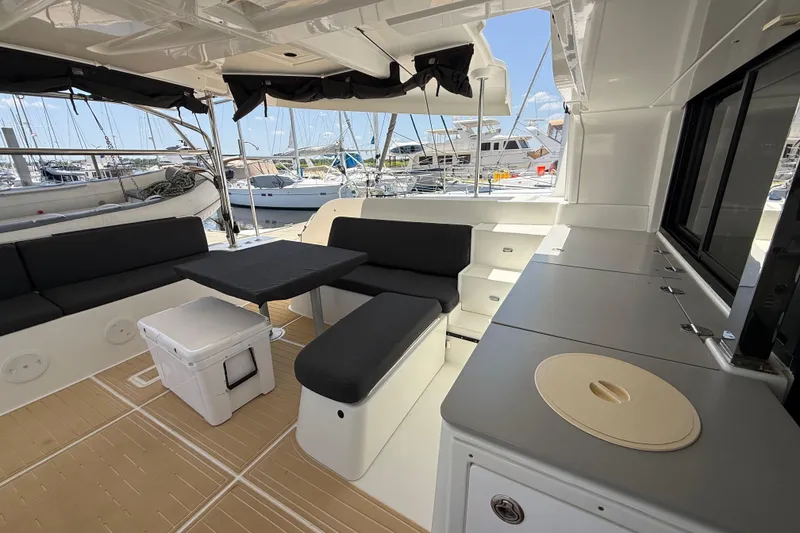 Slide: The Image of Spacious 2021 Lagoon 46 yacht cockpit with seating, table, and marina view. - 38