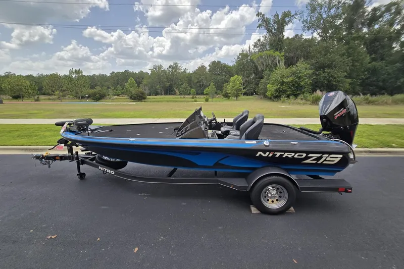 Slide: The Image of 2024 Nitro Z19 boat on trailer, parked on road with lush greenery background. - 5