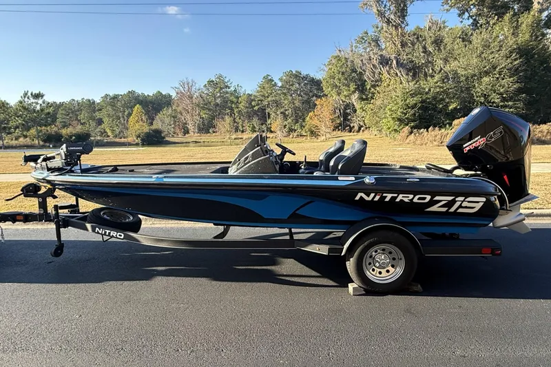 Slide: The Image of 2024 Nitro Z19 boat on trailer, parked on road with scenic background. - 8