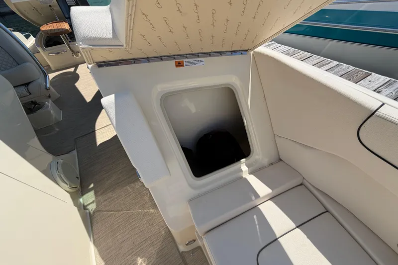 Slide: The Image of 2023 Chris-Craft Launch 28 GT interior storage compartment with open hatch, showcasing luxury seating. - 19