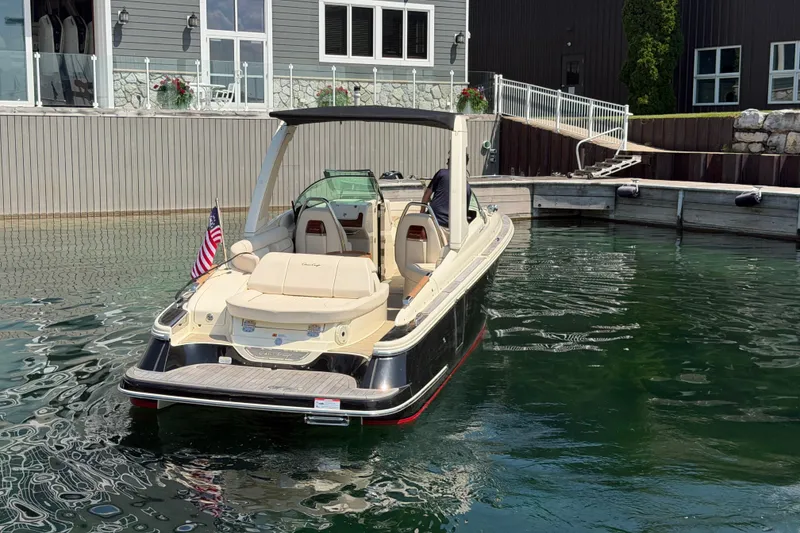 Slide: The Image of 2023 Chris-Craft Launch 28 GT boat docked in clear water near a modern building. - 1