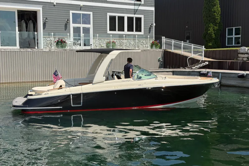 Slide: The Image of 2023 Chris-Craft Launch 28 GT boat docked by a modern waterfront building. - 2
