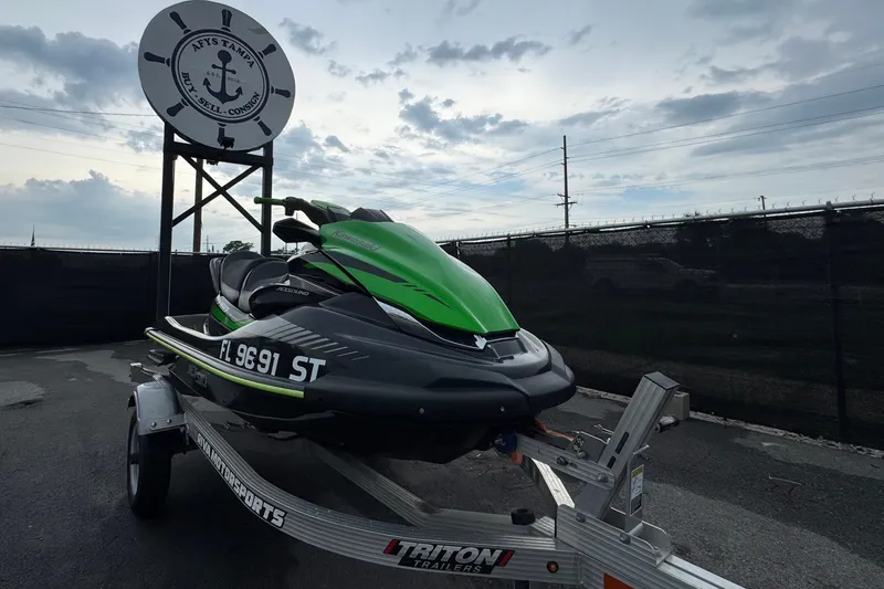 The Image of A green 2020 Kawasaki Jetski STX 160LX on a trailer in front of a sign. - 0