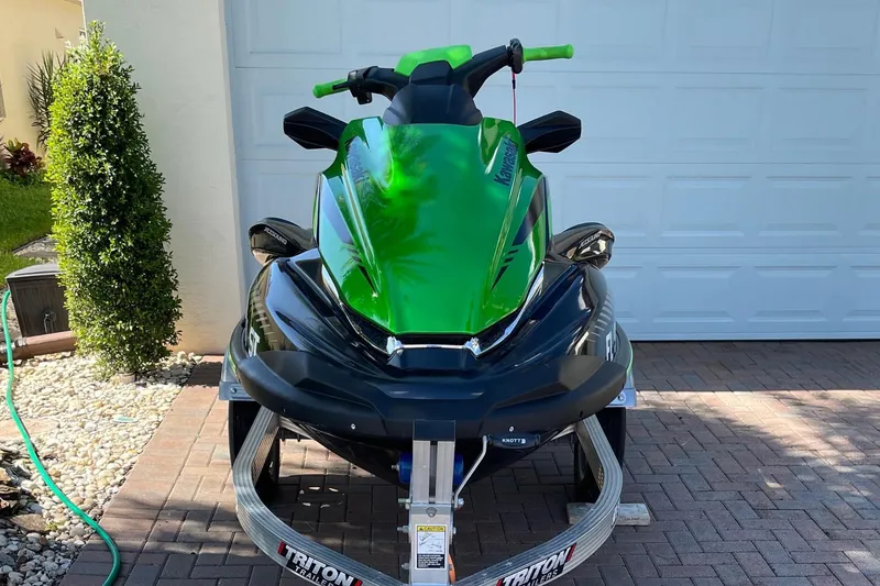 Slide: The Image of A green 2020 Kawasaki Jetski STX 160LX on a trailer in front of a garage. - 1