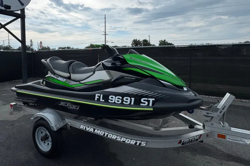 Slide: The Image of A 2020 Kawasaki Jetski STX 160LX on a trailer, parked near a sign with an anchor. - 1