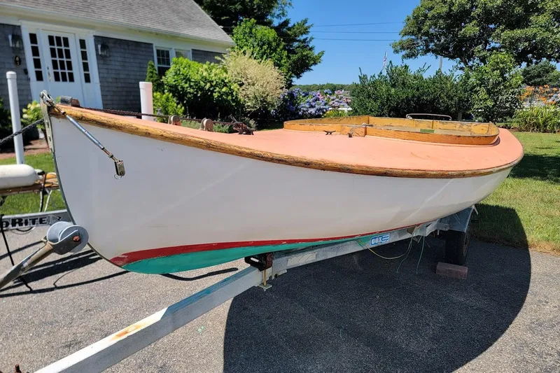 Slide: The Image of 1999 Beetle Cat 14 Classic sailboat on trailer, parked in a sunny garden setting. - 6