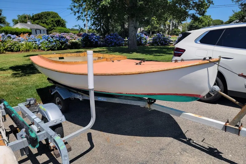 The Image of 1999 Beetle Cat 14 Classic sailboat on trailer, parked beside a white SUV in a garden setting. - 0
