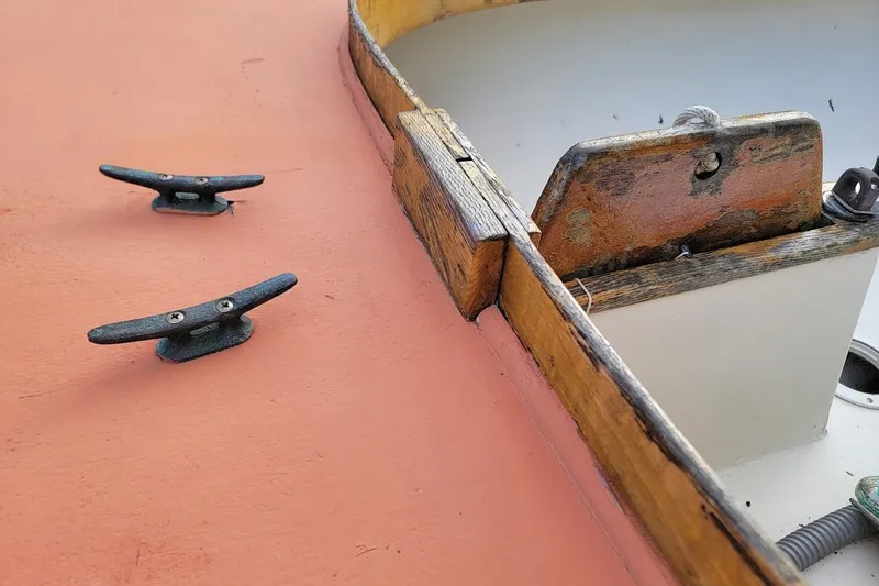 Slide: The Image of Close-up of a 1999 Custom Fiberglass Beetle Cat 12 boat deck with cleats and wooden trim. - 21