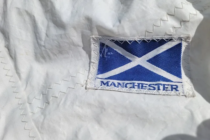 Slide: The Image of White fabric with blue Manchester patch featuring a white cross design. - 13