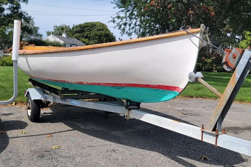 The Image of 1999 Custom Fiberglass Beetle Cat 12 sailboat on trailer, parked outdoors. - 0
