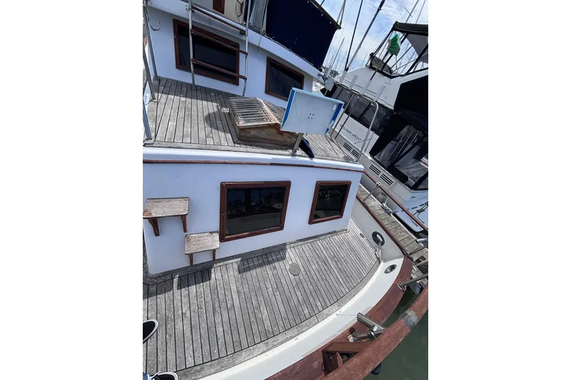 Slide: The Image of 1981 Hershine 40 boat with wooden deck and white cabin, docked at marina. - 44