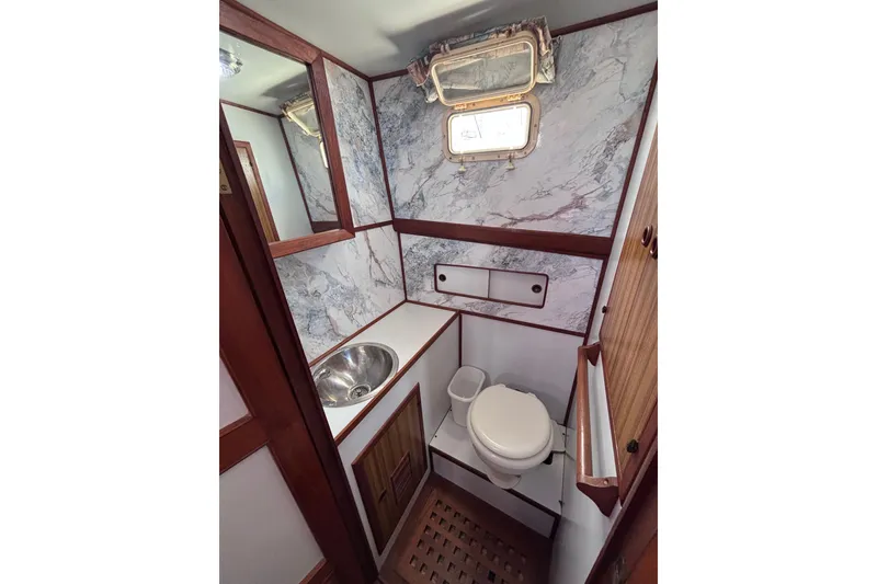 Slide: The Image of 1981 Hershine 40 yacht bathroom with marble walls, wooden accents, and stainless steel sink. - 19