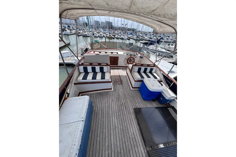 Slide: The Image of 1981 Hershine 40 boat deck with striped seating, docked in a marina. - 46