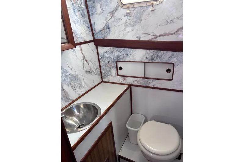 Slide: The Image of 1981 Hershine 40 yacht bathroom with marble walls, stainless steel sink, and compact toilet. - 20