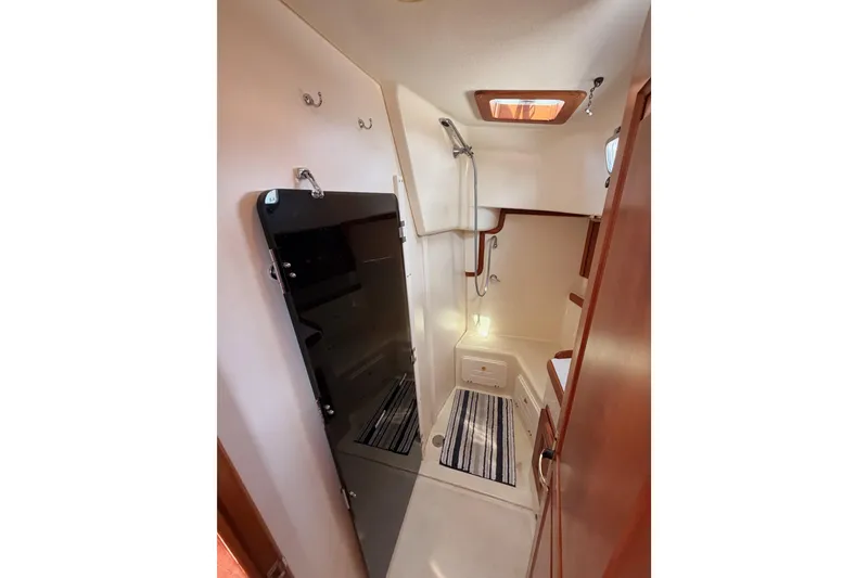 Slide: The Image of Interior of 2002 Tartan 3700 sailboat, featuring a compact bathroom with shower and wooden accents. - 54