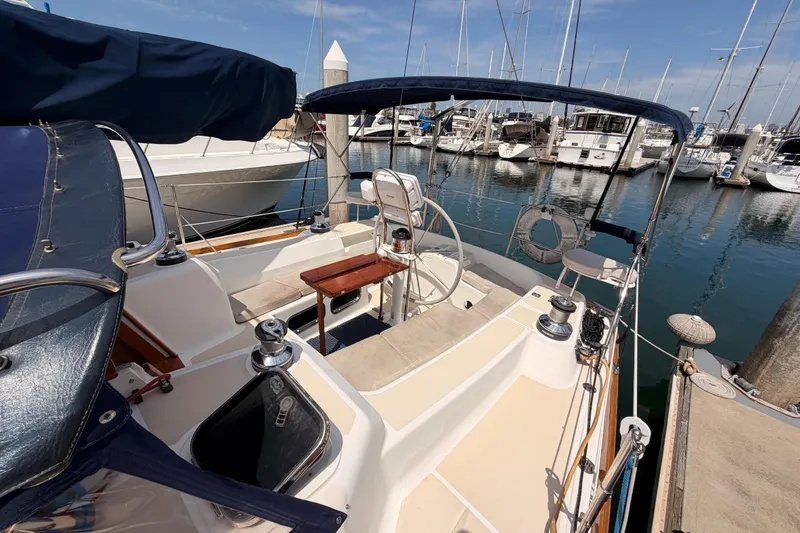 Slide: The Image of 2002 Tartan 3700 sailboat docked at marina, featuring spacious cockpit and steering wheel. - 25