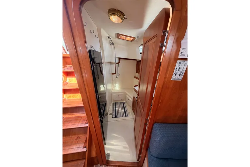 Slide: The Image of Interior of 2002 Tartan 3700 sailboat, featuring wooden cabinetry and compact bathroom. - 53