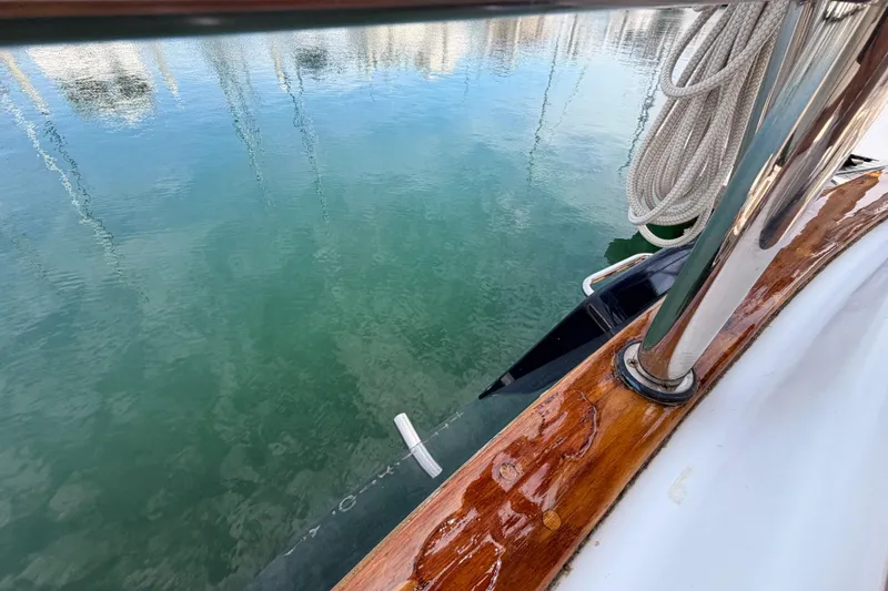 Slide: The Image of Tartan 3700 sailboat deck with polished wood and coiled rope, reflecting on calm water. - 32