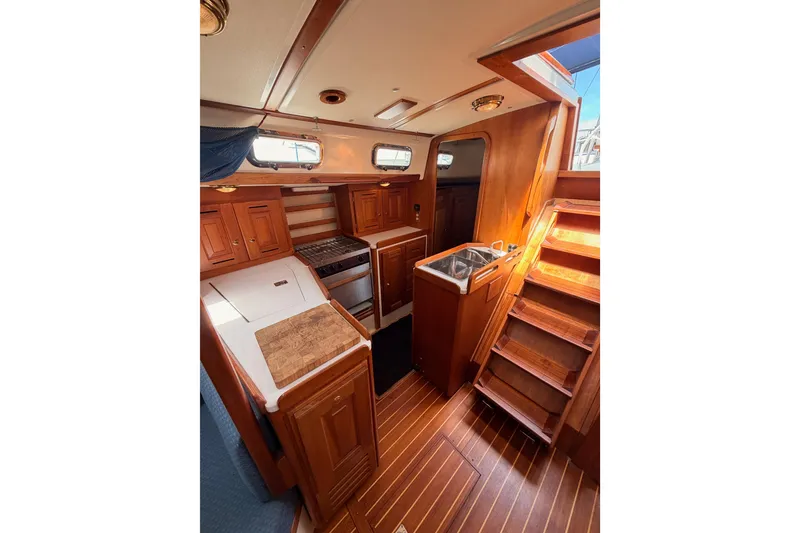 Slide: The Image of Interior of 2002 Tartan 3700 sailboat with wooden cabinetry and compact kitchen area. - 62