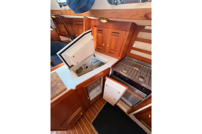 Slide: The Image of Interior of 2002 Tartan 3700 yacht kitchen with stove, fridge, and wooden cabinetry. - 63