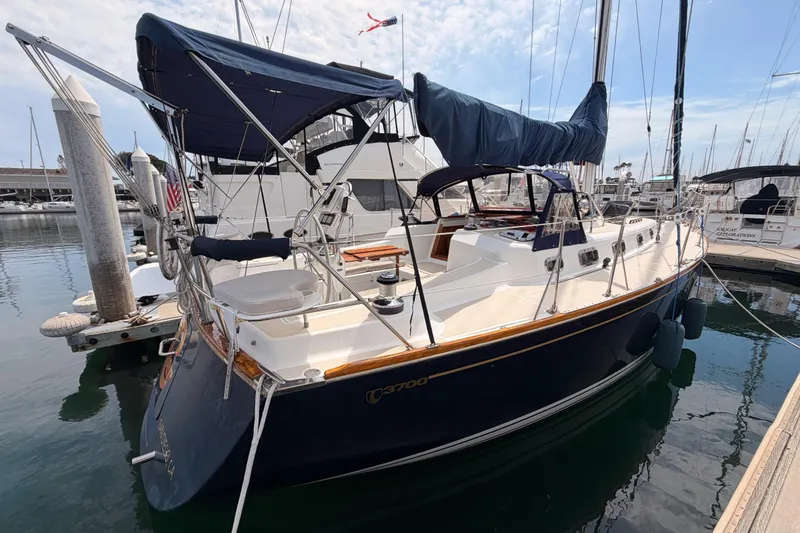 Slide: The Image of Sailboat Tartan 3700, 2002 model, docked in a marina with blue canopy. - 2