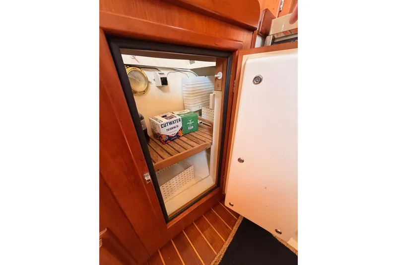Slide: The Image of Wooden cabinet interior on a 2002 Tartan 3700 yacht, featuring storage shelves and beverages. - 65