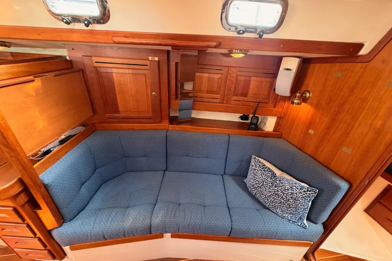 Slide: The Image of Cozy interior of 2002 Tartan 3700 sailboat with blue cushioned seating and wooden cabinetry. - 86