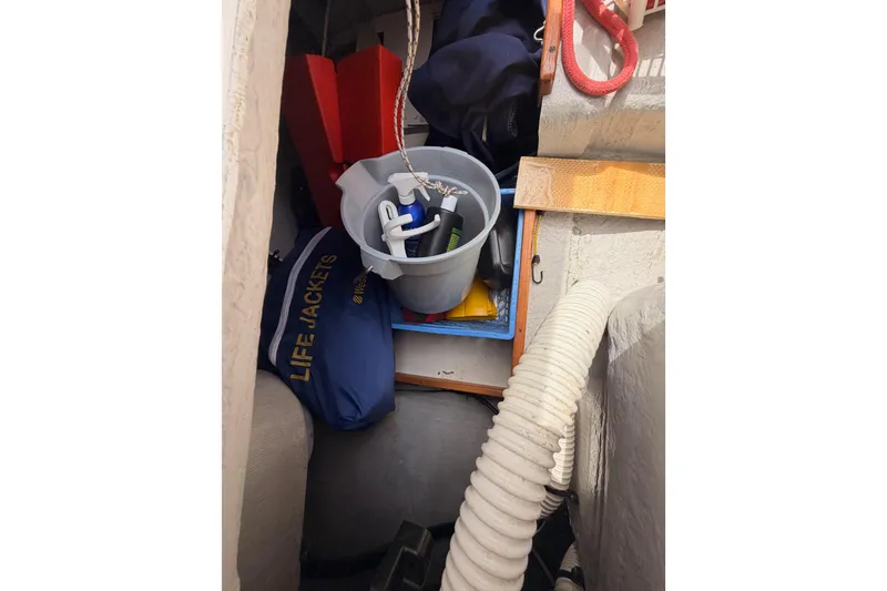 Slide: The Image of Storage area on a 2002 Tartan 3700 sailboat with life jackets and cleaning supplies. - 103