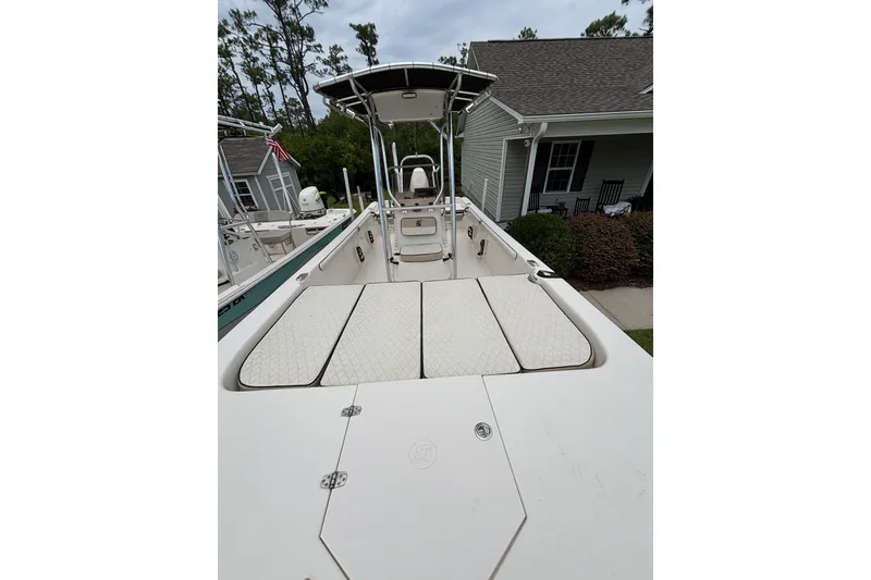 Slide: The Image of 2020 Carolina Skiff 21 LS boat with spacious deck and seating, parked near a house. - 4