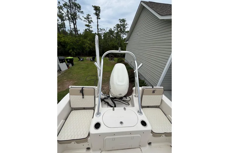 Slide: The Image of 2020 Carolina Skiff 21 LS boat interior with seating and motor, parked near a house. - 8