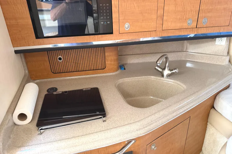 Slide: The Image of 2006 Searay 290 AMBERJACK boat kitchen with sink, stove, and wooden cabinets. - 27