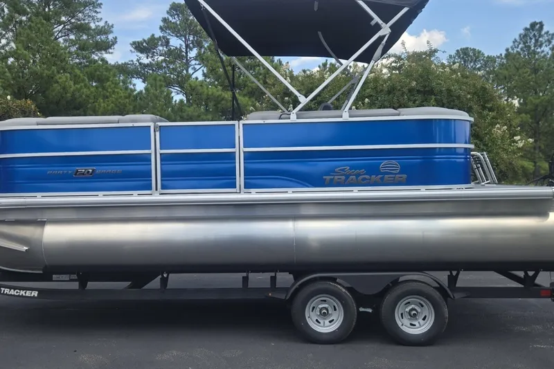 The Image of 2026 Sun Tracker Party Barge 20 DLX pontoon boat on trailer, parked outdoors. - 0