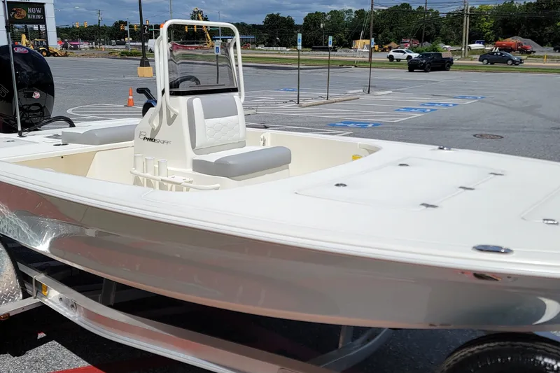 Slide: The Image of 2026 Mako 18 Pro Skiff boat in parking lot, showcasing sleek design and seating. - 2