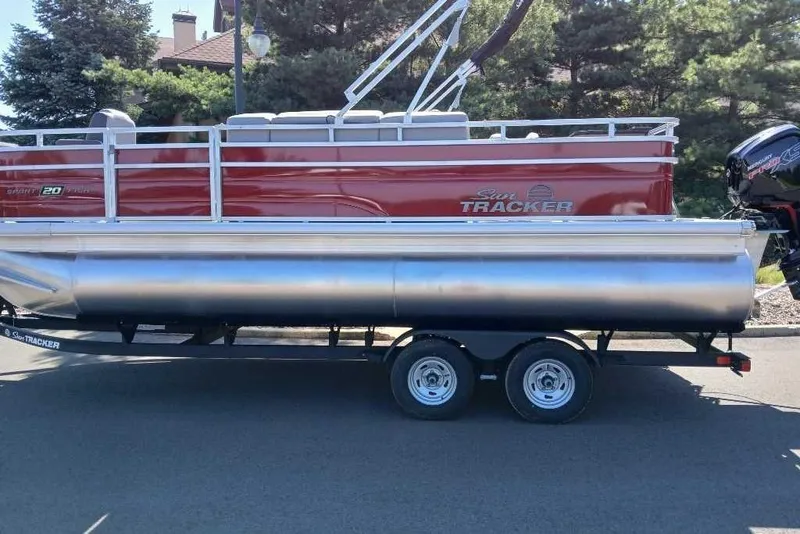 The Image of 2026 Sun Tracker SportFish 20 DLX pontoon boat on trailer, parked outdoors. - 0