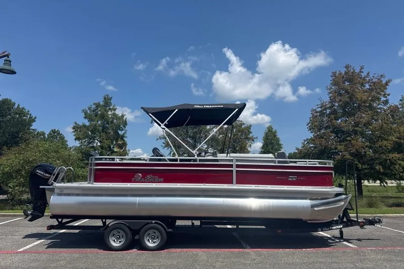 The Image of 2026 Sun Tracker Sportfish 24 XP3 pontoon boat on trailer under blue sky. - 0