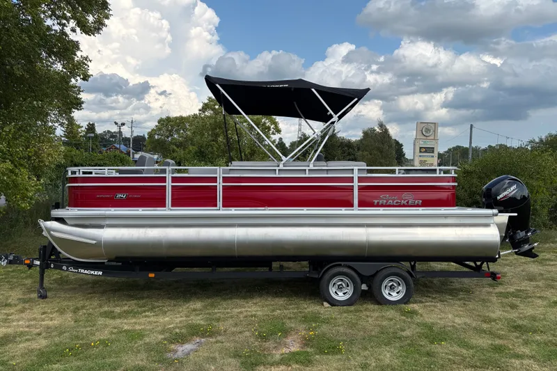 The Image of 2026 Sun Tracker Sportfish 24 XP3 pontoon boat on trailer, parked on grass. - 0