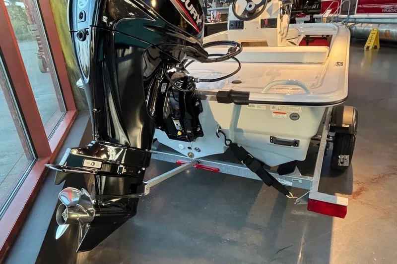 Slide: The Image of 2026 Mako Pro Skiff 13 CC boat with outboard motor on display indoors. - 12