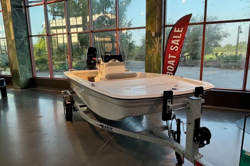 Slide: The Image of 2026 Mako Pro Skiff 13 CC boat on display indoors with a "Boat Sale" sign. - 1