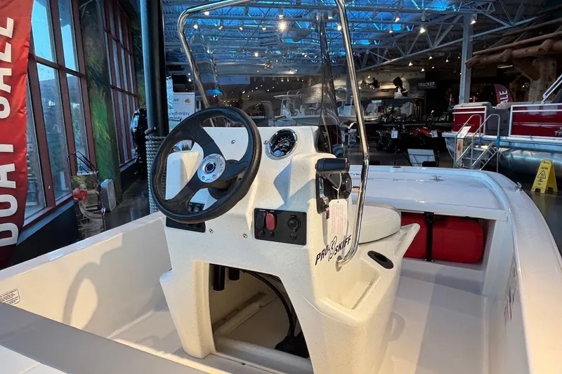Slide: The Image of 2026 Mako Pro Skiff 13 CC boat interior with steering wheel and console in showroom. - 9