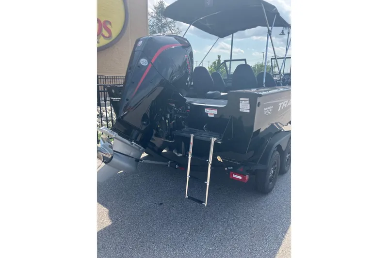 Slide: The Image of 2026 Tracker Targa V-19 Combo boat with outboard motor and ladder, parked outdoors. - 3