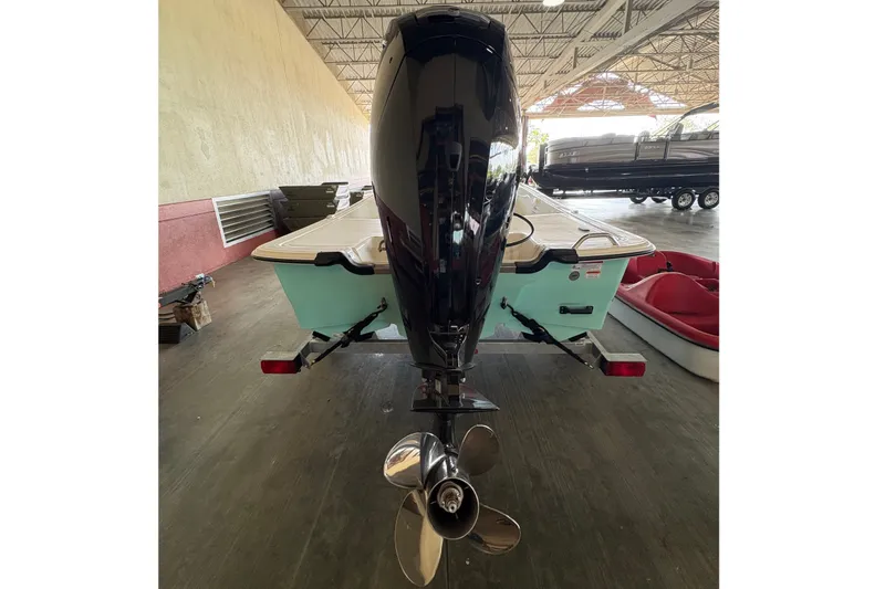 Slide: The Image of A 2026 Mako Pro Skiff 17 CC with an outboard motor and propeller, parked indoors. - 4