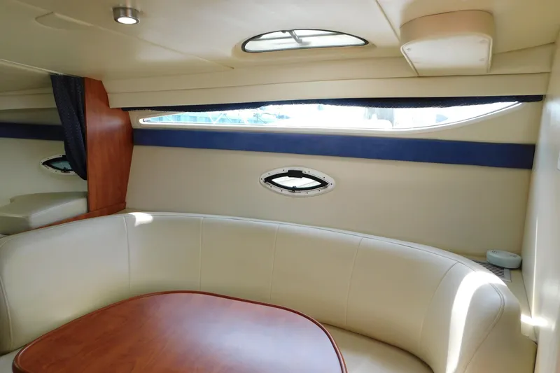Slide: The Image of Interior of 2009 Bayliner 300 boat with curved seating and wooden table. - 53